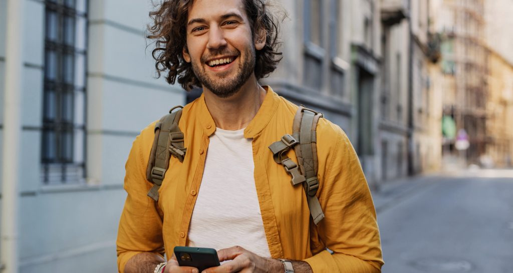 Smilende mann som sjekker mobilen etter å fått den beste renta på BSU kontoen sin i Sparebanken Øst.